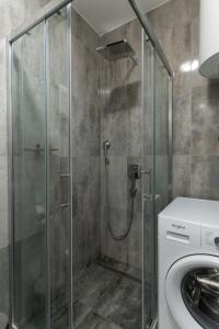 Una ducha con puerta de cristal al lado de una lavadora. en President Apartman 6, en Vračar (historical)