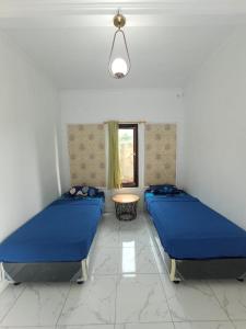 two beds in a room with a table and a window at RD Cottage Valley in Bogor