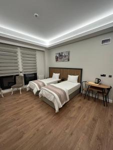 a bedroom with two beds and a table and a fireplace at Akel Guest House in Tekirdağ