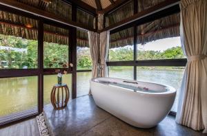 eine Badewanne in einem Zimmer mit großen Fenstern in der Unterkunft Vinpearl Resort & Spa Phu Quoc in Phu Quoc
