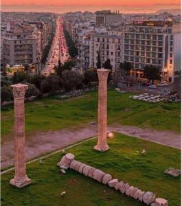 due colonne in un campo con una città sullo sfondo di The Athens Gate Hotel ad Atene