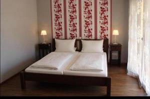 Ce lit se trouve dans un dortoir doté d'un mur rouge et blanc. dans l'établissement Apartments La Rosa, à Rust