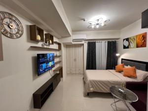 a bedroom with a bed and a clock on the wall at INSPIRiA TOWER CONDOMINIUM 1126 in Davao City