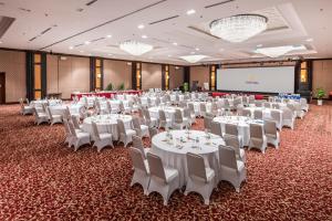 a banquet hall with white tables and chairs and a screen at Vinpearl Resort & Spa Phu Quoc in Phú Quốc +37 photos