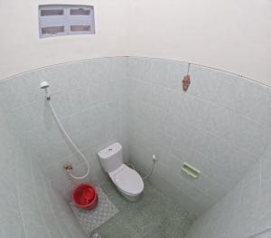 uma casa de banho com um WC branco e um balde vermelho em JE Homestay Jogja em Sentool