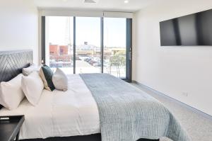a bedroom with a large bed with a large window at Indulge Apartments - City View Penthouses in Mildura