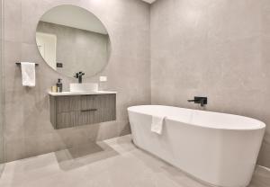 a bathroom with a tub and a sink and a mirror at Indulge Apartments - City View Penthouses in Mildura