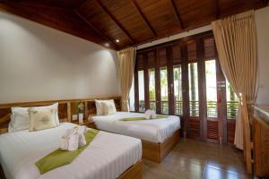 two beds in a room with windows at Madee Spa & Resort in Ban Khok Lo