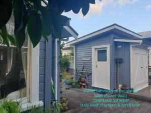 a blue shed with a white door in a yard at Cabins on Tudor bed & breakfast in Motueka