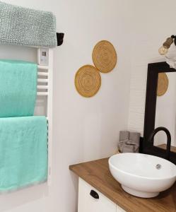 a bathroom with a sink and towels on the wall at Maison de vacances 2 chambres plages lac à 600m proche Dune du Pilat Océan dans propriété privée in Sanguinet