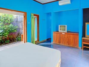 a bedroom with blue walls and a bed and a tv at OYO 92401 Hotel Mustika in Mendaya