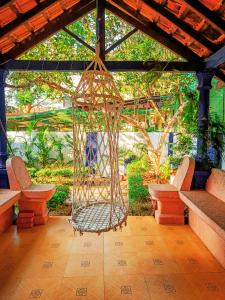 a hanging hammock in a patio with two benches at Casa Brooklyn Portuguese Heritage in Saligao