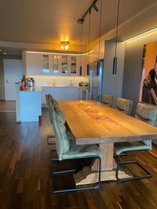 einen großen Holztisch mit Stühlen und eine Küche in der Unterkunft Holmestrand, leilighet på bryggekanten in Holmestrand