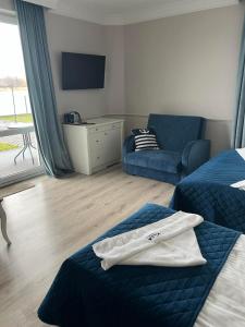 a room with two beds and a couch and a tv at Willa Aura Mare in Dziwnów