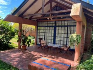 een overdekte patio met 2 stoelen en een bank bij Weaver Cottages in Harare