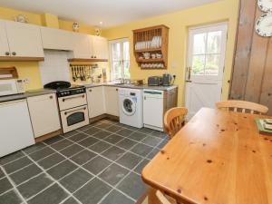 a kitchen with white appliances and a wooden table at Swallows in Saint Keverne