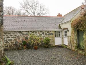 an old stone house with a garage and plants at Swallows in Saint Keverne