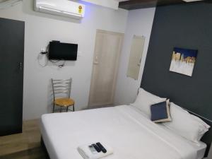 una camera con letto bianco e TV di Silver Cloud Hotel Sholinganallur a Chennai