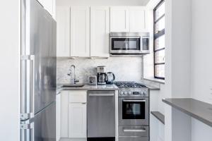 a kitchen with white cabinets and a stainless steel appliance at New W Village 2BR w WD Doorman nr Bars NYC-553 in New York