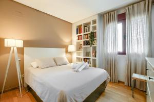 1 dormitorio con cama blanca y estante para libros en Apartamento en Chamberí con piscina - Lovely apartment in the City Center with swimming pool, en Madrid