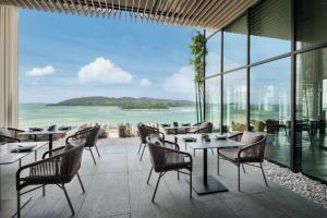 コタキナバルにあるHyatt Centric Kota Kinabaluのテーブルと椅子が備わり、海の景色を望むレストラン