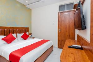a bedroom with a bed with red pillows and a television at Hotel Purple Orchid in Mumbai