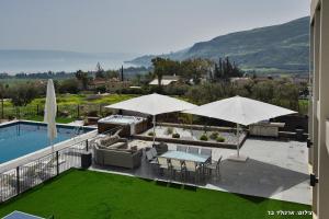 um pátio com mesas e guarda-sóis ao lado de uma piscina em Villa J em Migdal
