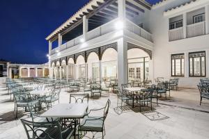 an empty patio with tables and chairs at night at Grupotel Club Menorca in Son Xoriguer