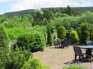 a patio with tables and chairs in a garden at 4 Sterne App Lavendel IR-Sauna Whirlpool Fitnessraum kinderfreundlich Bikeraum in Hahnenklee-Bockswiese