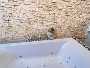 a white bath tub in a bathroom with a stone wall at 4 Sterne App Lavendel IR-Sauna Whirlpool Fitnessraum kinderfreundlich Bikeraum in Hahnenklee-Bockswiese +20 photos