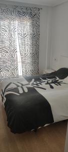 a bedroom with a bed with a black and white blanket at apart paz in Torrevieja