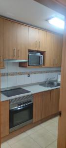 a kitchen with a sink and a stove and a microwave at apart paz in Torrevieja