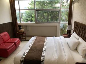 a bedroom with a large bed and a red chair at Muzaffarabad View Motel in Muzaffarabad