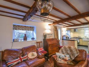 een woonkamer met lederen meubels en een keuken bij Naunton Cottage in Lyme Regis