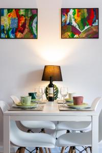 mesa de comedor blanca con sillas y lámpara en Warzywnicza Apartment Motława River by Renters en Gdansk