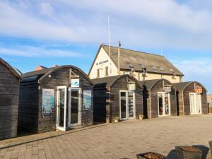 a row of wooden buildings in front of a building at Driftwood Apartment in Amble