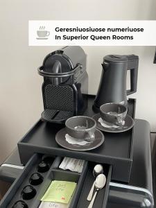 eine schwarze Kaffeemaschine und zwei Tassen und Untertassen in der Unterkunft GRAND CROWN in Vilnius