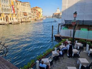 a group of people sitting at tables next to a river at Luxury apartment in Venice in Venice