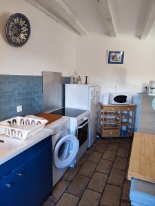 uma cozinha com uma máquina de lavar roupa e um frigorífico em Gite les Olivettes em Vailhan