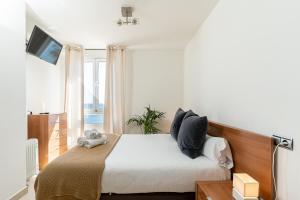 Schlafzimmer mit einem Bett mit weißer Bettwäsche und einem TV in der Unterkunft MONKÓ ON THE ROCK in Torremolinos + 37 Fotos