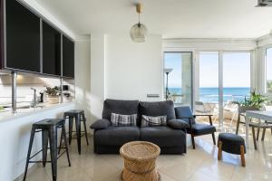 ein Wohnzimmer mit einem Sofa und eine Küche mit Meerblick in der Unterkunft MONKÓ ON THE ROCK in Torremolinos