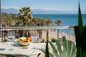 einen Tisch mit zwei Weingläsern und einer Obstschale in der Unterkunft MONKÓ ON THE ROCK in Torremolinos