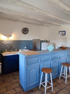 uma cozinha azul com um balcão e dois bancos em Gite les Olivettes em Vailhan