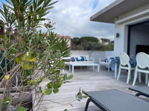 eine Terrasse mit weißen Stühlen, Tischen und einer Pflanze in der Unterkunft La Sté in Porticcio