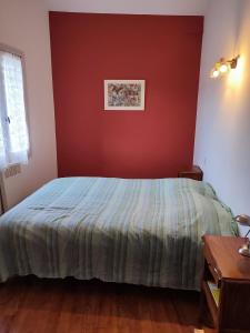 1 dormitorio con cama y pared roja en Gite les Olivettes, en Vailhan