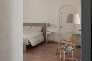 ein Schlafzimmer mit einem Bett, einem Stuhl und einem Tisch in der Unterkunft Il Vicinato, casa vacanza immersa nel cuore dei Sassi in Matera