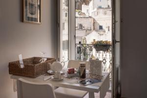 Zimmer mit einem Tisch, Stühlen und einem Fenster in der Unterkunft Il Vicinato, casa vacanza immersa nel cuore dei Sassi in Matera