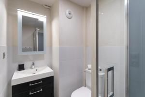 La salle de bains blanche est pourvue d'un lavabo et d'une douche. dans l'établissement La Tourelle & l'Honoré - 2 appartements dans le Centre historique de Rennes, à Rennes