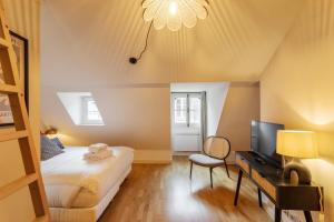 een slaapkamer met een bed en een bureau met een televisie bij La Tourelle & l'Honoré - 2 appartements dans le Centre historique de Rennes in Rennes