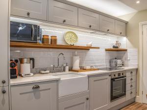 a kitchen with white cabinets and a sink and a microwave at The Coach House in Whitstable